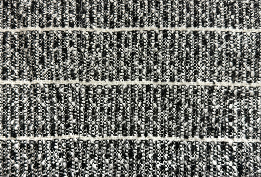 Close up texture of black and white boucle fabric. Curled and nubby knitted tufted texture. Suitable for sofa, upholstery, curtain, and drapery. Seamless background fabric texture.