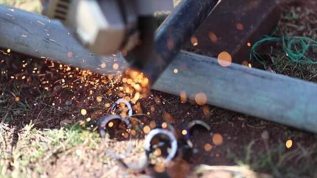 Man is cutting a metal list by angle grinder saw.