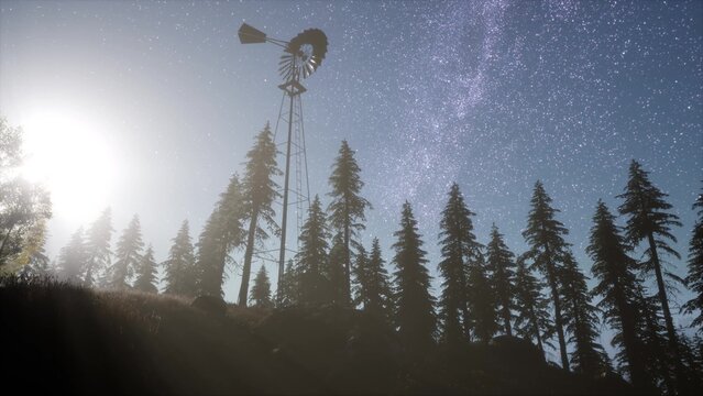 A striking silhouette of a vintage windmill stands against a stunning night sky filled with stars. Tall evergreen trees frame the scene, while the soft glow of a distant sun adds warmth.