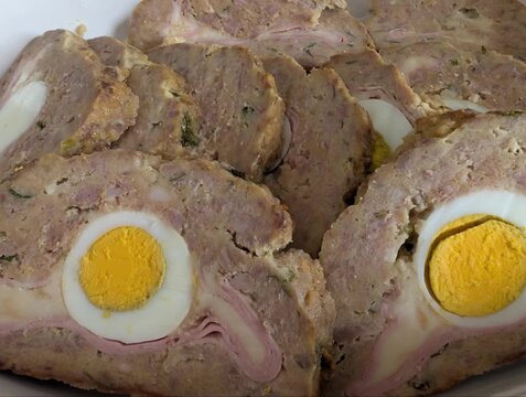 Polpettone fatto in casa con uova sode al centro, tagliato a fette per mostrare il ripieno
