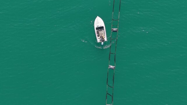Aerial shot of boat and buoy line creating pattern on calm turquoise sea