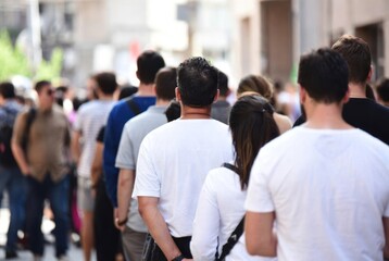 Obraz premium Diverse Crowd Waiting in Line Outdoors on a Bright Sunny Day in a City Street