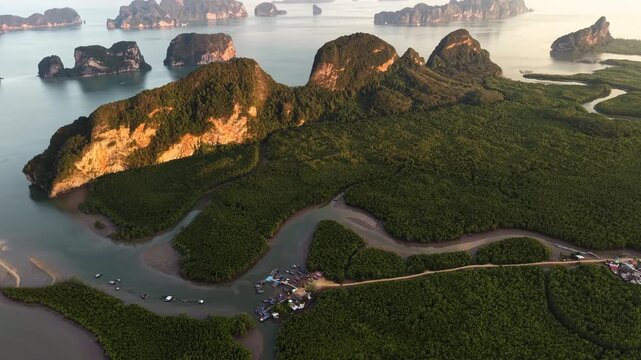 jagged limestone karst peaks rising from a dense mangrove forest at sunset.