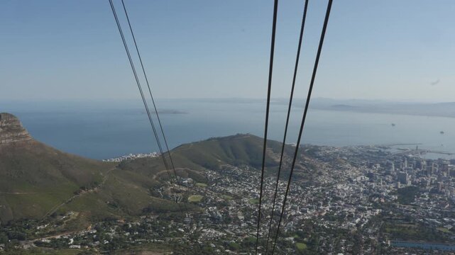 Cable car lines descending from Table Mountain toward Cape Town with sweeping coastal city panorama, South Africa