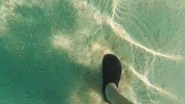 A captivating underwater view at Bamboo Island, Thailand. Watch as feet tread gently through clear, sunlit waters, revealing the sandy seabed below. Perfect for travel and nature projects.