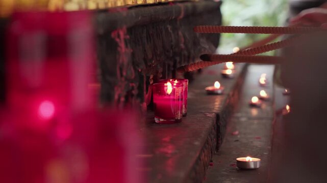 Close-up static shot of hands lighting a red incense stick with a flame at Luohan Temple in Chongqing, warm and devotional atmosphere with shallow depth of field