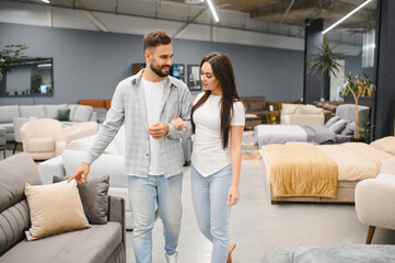 Fototapeta premium Young couple choosing furniture in store for home