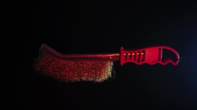 new metal brush with red handle, 360 degree rotation on a dark background with red backlight