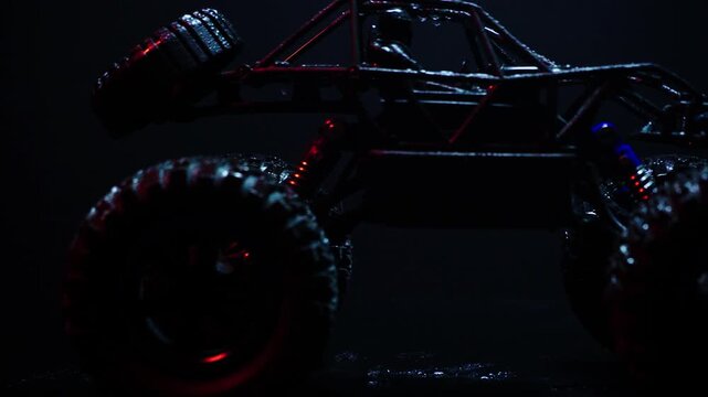 off-road toy cars turn with big tires art creative in water splashes 360 degree rotation on dark background with red backlight