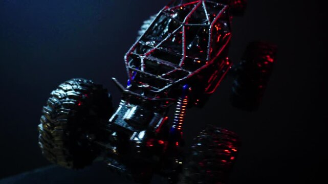 off-road toy cars turn with big tires art creative in water splashes 360 degree rotation on dark background with red backlight
