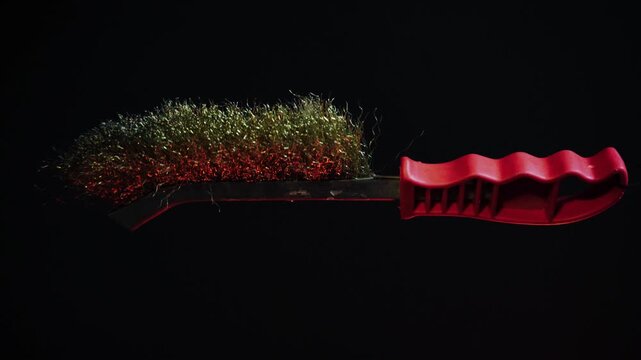 new metal brush with red handle, 360 degree rotation on a dark background with red backlight