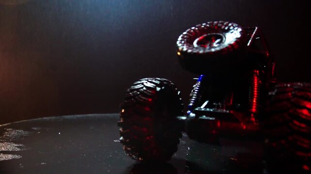 off-road toy cars turn with big tires art creative in water splashes 360 degree rotation on dark background with red backlight