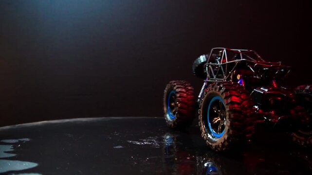 off-road toy cars turn with big tires art creative in water splashes 360 degree rotation on dark background with red backlight