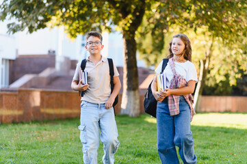 Obraz premium Schoolchildren walking on campus with backpacks and books