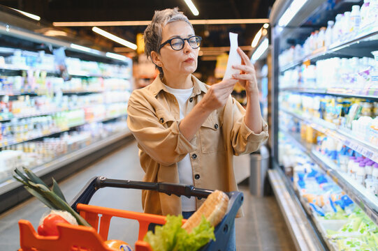 Woman checking shopping list in grocery store aisle