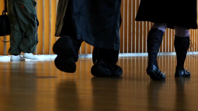 People walking in front of wooden vertical slats wall in slow motion, warm lighting and urban atmosphere. Suitable for lifestyle, business and cinematic background footage.