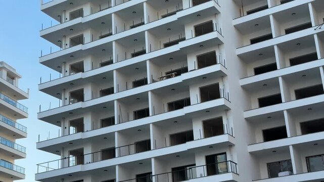Modern apartment building exterior with rows of balconies against clear blue sky