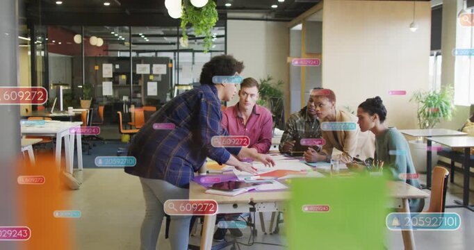 Presenter leaning over table, placing colored sheets and pointing, team examining layout for design