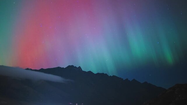 A timelapse of Vivid Multicoloured Aurora Australis Green Red and Cyan Over Mountain Silhouette New Zealand