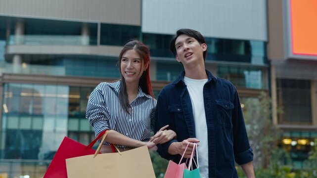 Beautiful Asian couple enjoy shopping together,young couple holding shopping bags,red bag,gold bad,Couple looking on the shopwindow while standing with shopping bags near the mall,christmas shopping