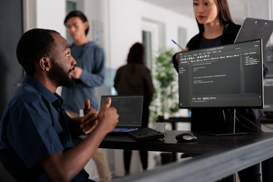 Diverse group of web developers analyzing html code and comparing data script in big data office room. Cloud programers working on system interface algorithm in development company.