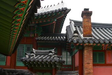 Obraz premium Complex of Traditional Korean Palace Architecture: Layered Tiled Roofs, Dancheong, and Red Brick Chimney at Changdeokgung