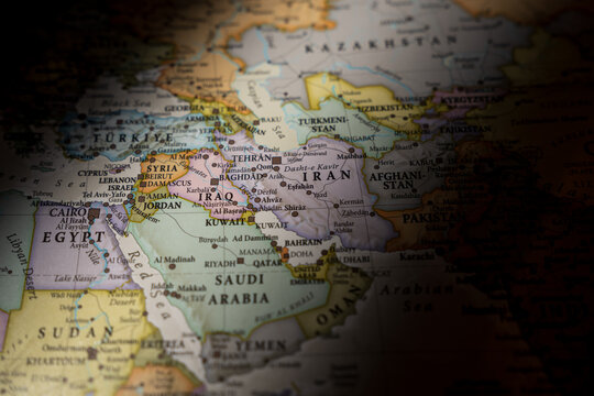 Dramatically lit world map focusing on Iran and the Middle East region, highlighting geopolitical hotspots and international borders in shadow