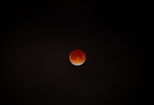 View of a blood moon glows eerily against the inky black canvas of the night sky, a celestial spectacle, Los Angeles, California, United States.