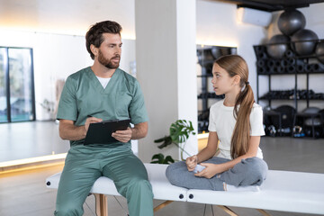 Male doctor talking to young girl during consultation