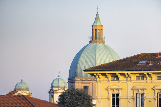 View of an ancient dome with its copper patina glowing warmly in the soft afternoon light, contrasting with the building's facade, Lucca, Tuscany, Italy.