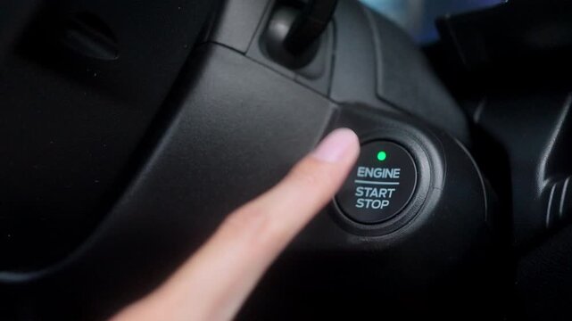 Detailed close-up of a driver's finger about to push a car's modern engine start stop button, highlighting ignition control and convenient automotive tech.