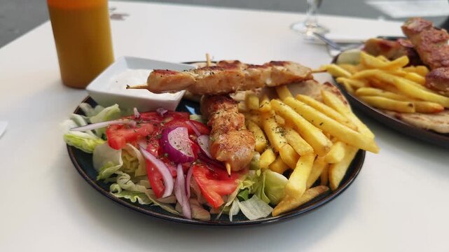 Greek pita, chicken souvlaki, green salad with fresh vegetables, French fries, and tzatziki sauce. Greek cuisine. High quality 4k footage