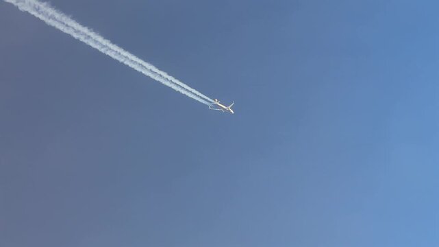 Cockpit View of a jet airplane and its contrail flying through ethereal clouds, crossing the screen in diagonal.
