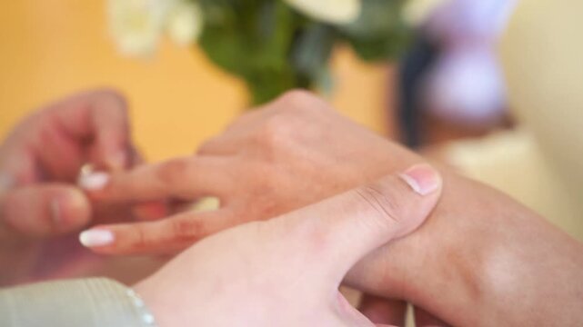 Couple's hands wearing engagement and wedding rings, symbolizing love, commitment, and marriage. A close-up view of joining hands