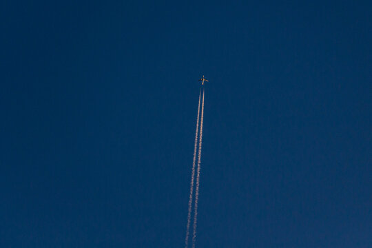 View of a jet plane soaring, leaving delicate white contrails etched against the deep blue canvas of the sky, Hunza Nagar, Gilgit, Pakistan.