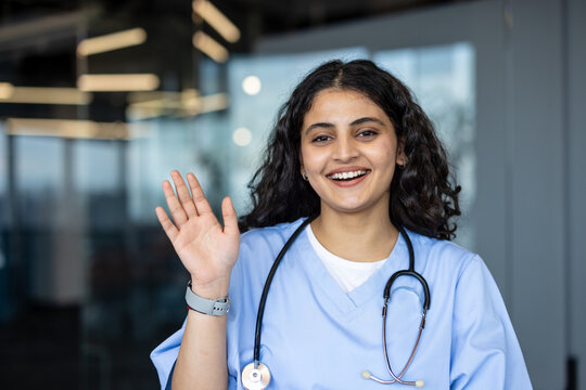 Young female doctor smiling and waving hand greeting