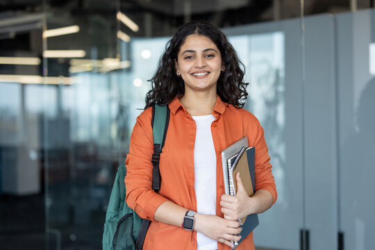 Young indian student smiling and holding notebooks