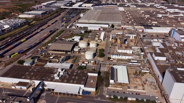 Aerial view of a large industrial complex with storage tanks, processing units, pipe racks and rail logistics yard, highlighting integrated supply chain and heavy industry infrastructure