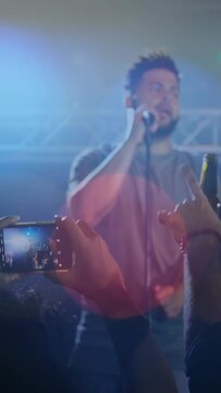 Vertical video: Music fan phone raising capturing singer moving center singing engaging fans lights