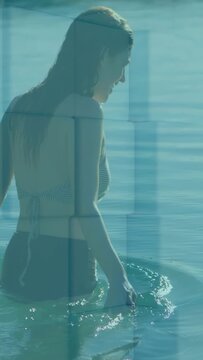 Vertical video: Woman stepping, wading sea, making ripples as rects overlaying water for design