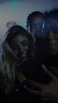 Vertical video: Friends checking phone at gig then turning toward singer appearing to watch show