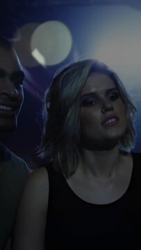 Vertical video: Woman gazing stage, man coming sparking flares and guitar riff causing music cheer