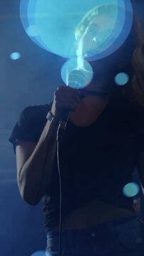 Vertical video: Hand gripping mic starting blue orbs as singer in rehearsal tilting cam moving