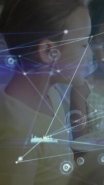 Vertical video: Two girls sitting hand motion initiating HUD with nodes and graphs learning tech