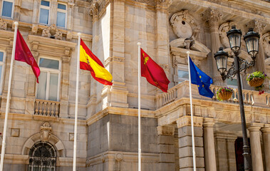 The flags of Spain including the European union flying outside of a Spanish government building.