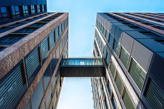 Modern brick buildings with glass skybridge in Dublin Ireland, contemporary urban architecture and clear blue sky.