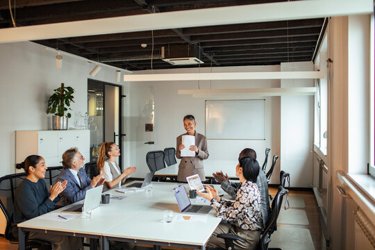 Business team applauding presenter in modern conference room