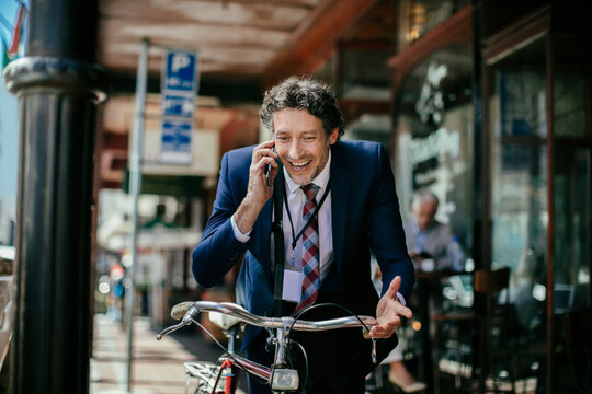 Businessman on phone with bicycle in city street