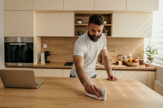 Young male cleaning kitchen countertop
