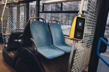 Fototapeta premium A travel card reader against the backdrop of a bus interior and empty seats, symbolizing the convenience of using modern public transport and cashless payments.